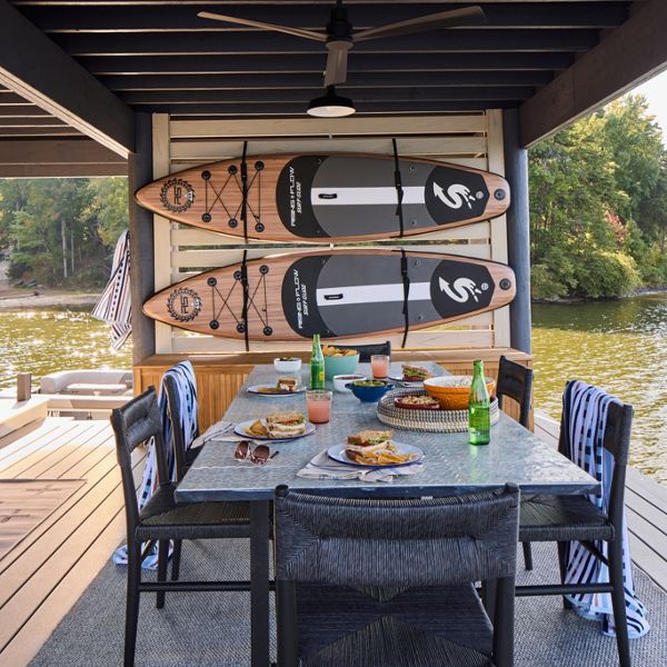 A view of the dock where tere is a dining table and two boats hanging on the wall.